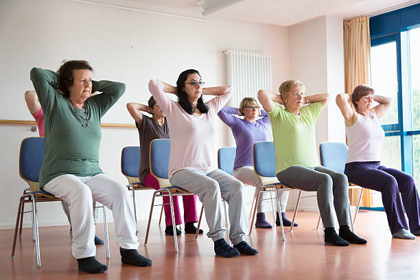 active senior women yoga class on chairs stock photo