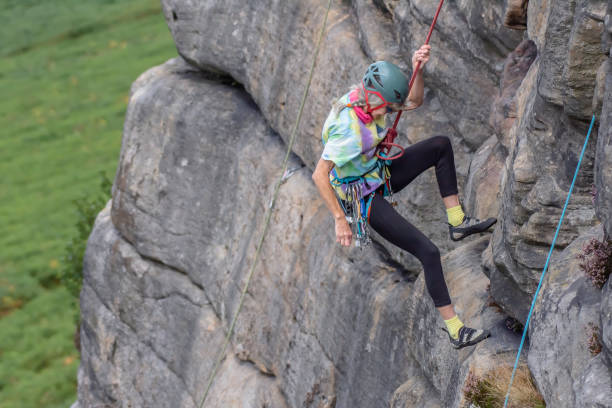 Active senior.Mature woman-rock climber descending down the cliff attached to safety rope. stock photo