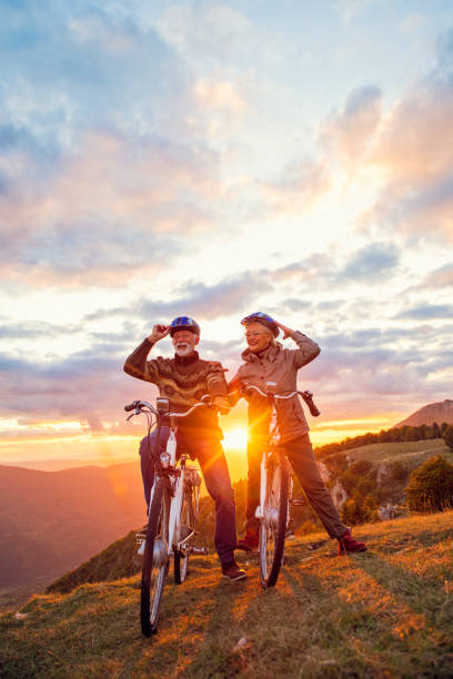 Active seniors having walk with bike in autumn nature. They having romantic time outdoor. stock photo