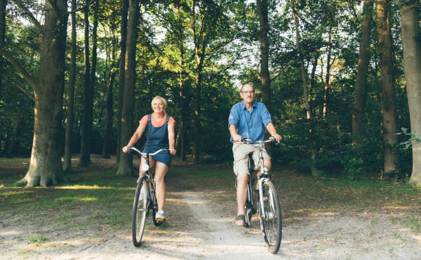 actieve senioren die fiets in de zomernatuur. oude mensen gezonde levensstijl, sport en duurzaam leefconcept - pensioen nederland stockfoto's en -beelden