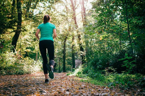 Active young woman running though the green nature stock photo