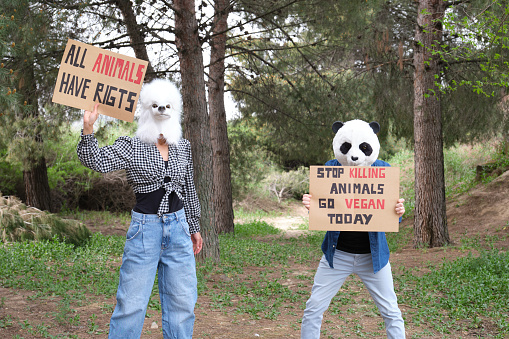 Activist protesters wearing animal masks to highlight cruelty and promote vegan lifestyle. Animal rights protest in a forest.