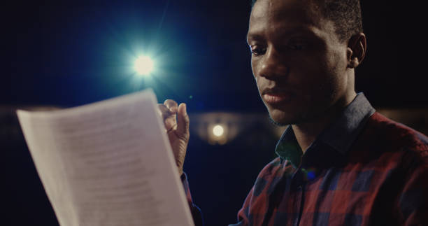 Actor performing a monologue in a theater Medium close-up shot of an actor performing a monologue in a theater while holding his script film script stock pictures, royalty-free photos & images