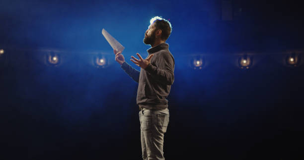 Actor performing a monologue in a theater Medium shot of an actor performing a monologue in a theater while holding his script actor stock pictures, royalty-free photos & images