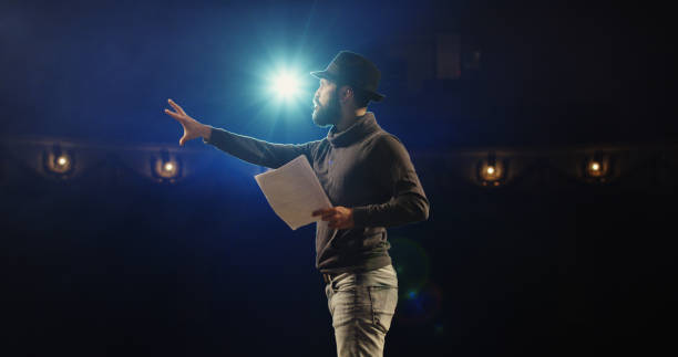 Actor performing a monologue in a theater Medium shot of an actor performing a monologue in a theater while holding his script actor stock pictures, royalty-free photos & images