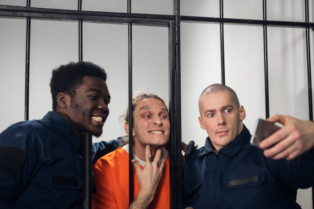 schauspieler am set eines films über das gefängnis machen ein lustiges selfie in einer gefängniszelle vor dem hintergrund von bars - cyber crime capture stock-fotos und bilder