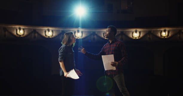 Actors rehearsing a scene in a theater Medium shot of an actor and actress rehearsing a scene in the theater while holding their scripts actor stock pictures, royalty-free photos & images