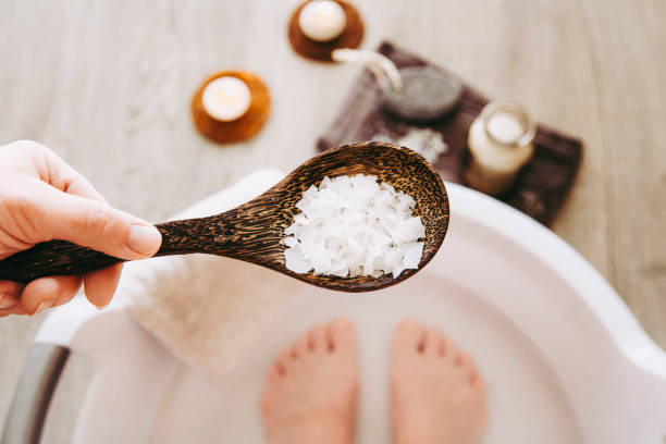 Adding Magnesium Chloride vitamin salt in foot bath water, solution. Magnesium grains in foot bath water are ideal for replenishing the body with this essential mineral, promoting overall wellbeing. Adding Magnesium Chloride vitamin salt in foot bath water, solution. Magnesium grains in foot bath water are ideal for replenishing the body with this essential mineral, promoting overall wellbeing. bathtub stock pictures, royalty-free photos & images