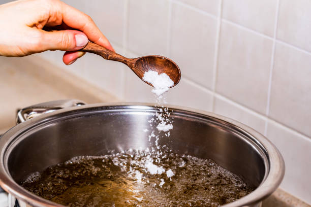 Adding salt in boiling water, cooking soup stock photo