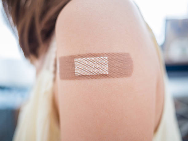 pflaster auf eine weibliche arm nach der impfung - pflaster stock-fotos und bilder
