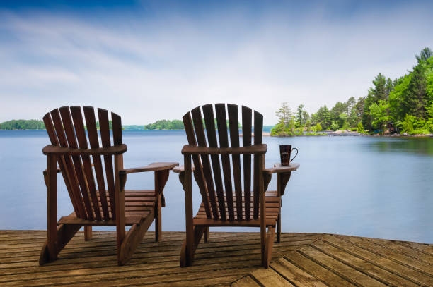 Adirondack chairs on a wooden dock on a calm lake in Muskoka stock photo