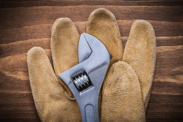 Adjustable spanner leather protective gloves on wooden board...