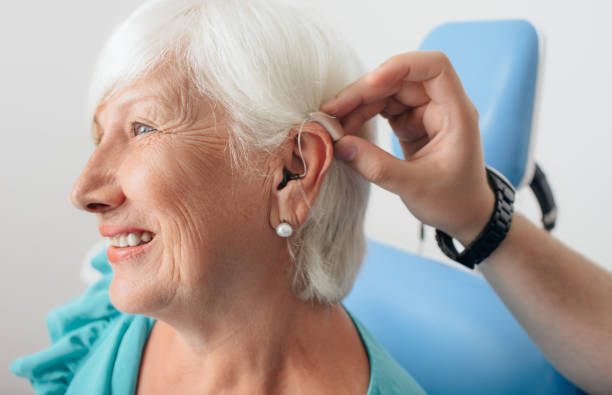 ajuste de un audífono para una mujer de edad - hearing aids fotografías e imágenes de stock