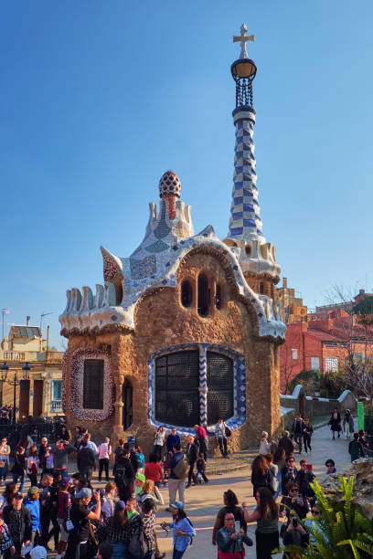 Administration office at the entrance of the Park Guell. Building with pinnacle and five-pointed cross designed by Antoni Gaudi with a crowd of tourists around. March 2017, Barcelona, Spain - Administration office at the entrance of the Park Guell. unesco organised group stock pictures, royalty-free photos & images