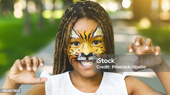 istock Adorable african-american girl with creative face painting roaring 1152817803