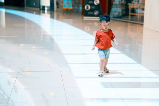 Adorable asian boy running happily inside a mall stock photo