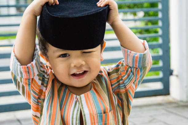 Adorable asian boy wearing traditional malay attire being playful at home stock photo