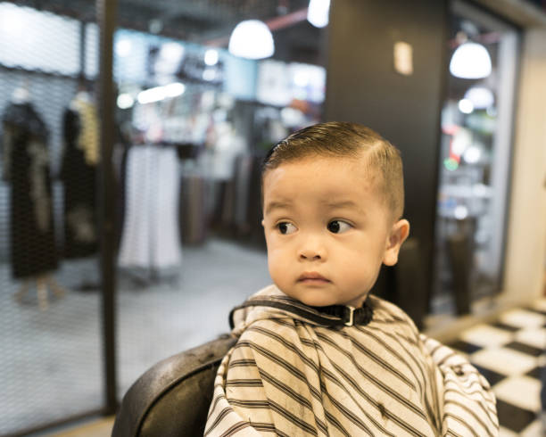 Adorable baby boy having a haircut at the barbershop stock photo
