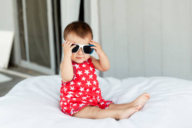 Adorable baby girl wearing red dress and sunglasses on Independence Day on 4th of July stock photo