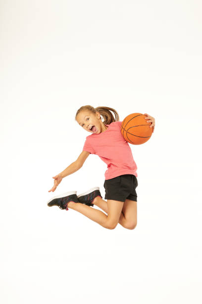 Adorable girl with basketball ball jumping and screaming with joy stock photo