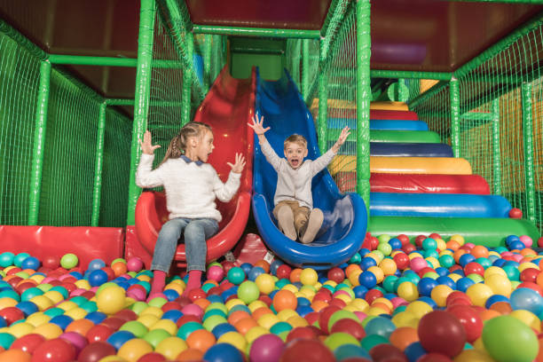 adorable happy little kids sliding in pool with colorful balls adorable happy little kids sliding in pool with colorful balls indoor playground stock pictures, royalty-free photos & images