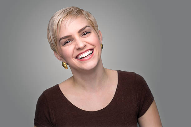 Adorable laughing head shot short pixie haircut modern gray background stock photo