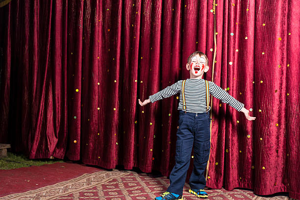 Adorable little boy singing on stage during a play Adorable little boy singing on stage during a play standing with outstretched arms in his costume and makeup in front of the burgundy colored curtain young male actors stock pictures, royalty-free photos & images