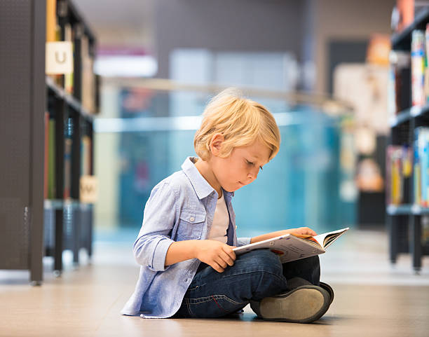 Adorable Little Boy Sitting In Library stock photo