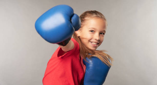 Adorable little girl boxer practicing punches in studio stock photo