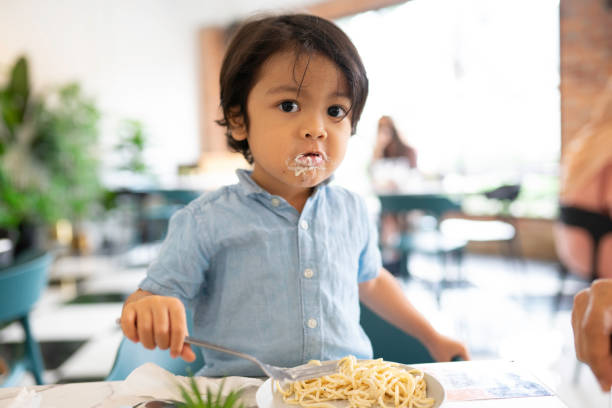 Adorable malay boy enjoying his lunch at a local restaurant stock photo