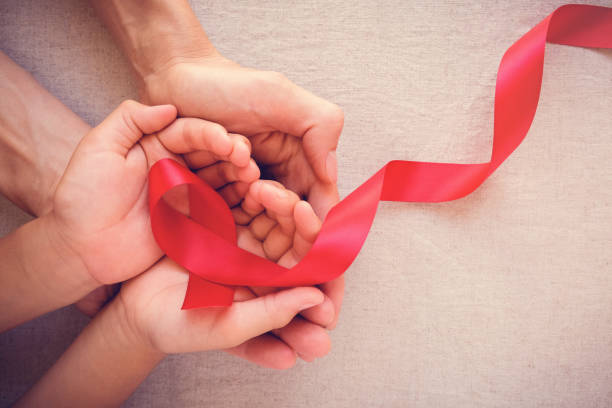 adult and child hands holding red ribbon, hiv awareness concept, world AIDS day stock photo