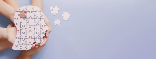 Adult and children hands holding brain with puzzle paper cutout, autism, memory loss, dementia, epilepsy and alzheimer awareness, world mental health day concept stock photo