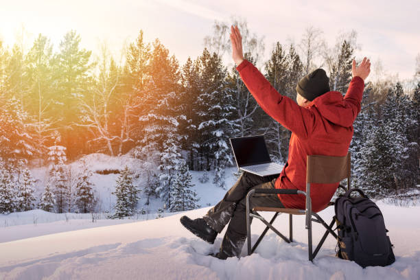 Adult man blogger or freelancer working on a laptop in winter forest. Freedom, remote work concept. stock photo