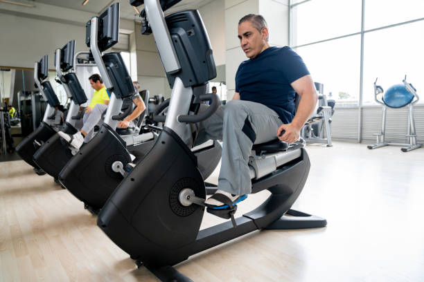 Adult man exercising at the gym using a recumbent bike Latin American adult man exercising at the gym using a recumbent bike - fitness concepts stationary bike stock pictures, royalty-free photos & images