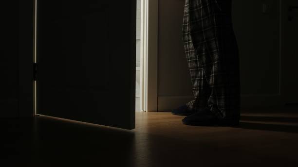 l’homme adulte dans un pyjama marche à une salle de bains dans la nuit - porte salle de bain photos et images de collection