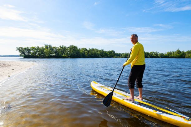 Adult man sails on a SUP board in large river and enjoying life stock photo