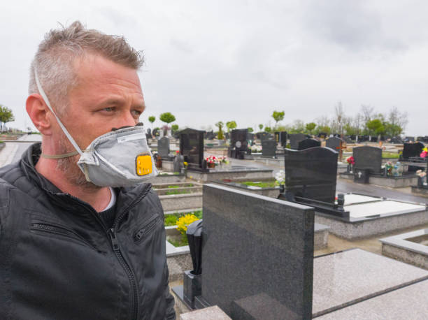 adult man wearing protective respiratory mask on his face at graveyard - covid cemiterio imagens e fotografias de stock
