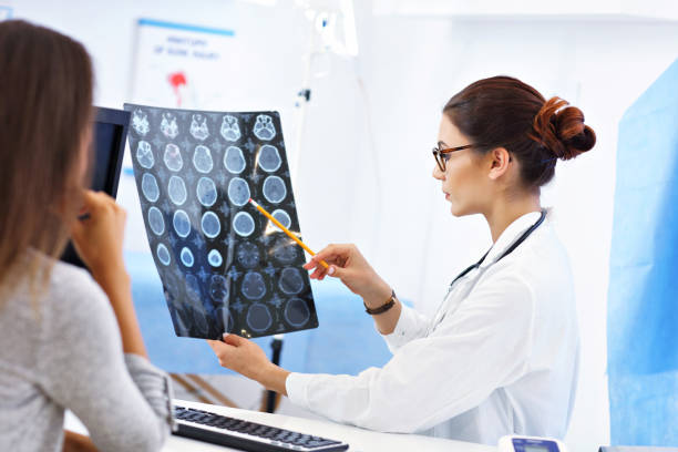 Adult woman discussing x-ray results during visit at female doctor's office Picture of adult woman having a visit at female doctor's office neurologist stock pictures, royalty-free photos & images