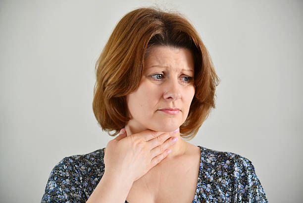 Adult woman with a sore throat on  light background stock photo