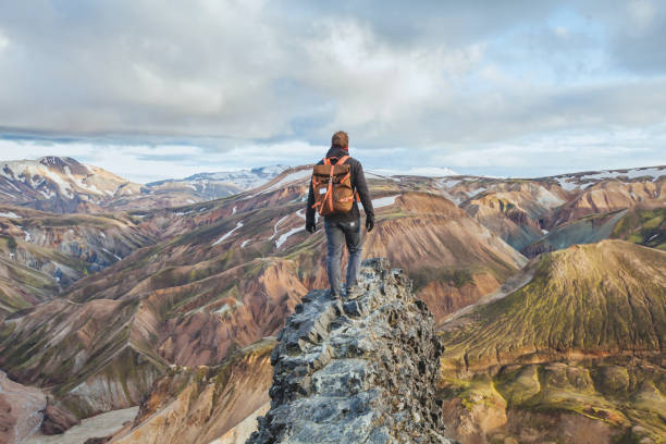adventure travel, hiking in Iceland with backpack, tourist adventure travel, hiking in Iceland with backpack, tourist looking at colorful landscape of Landmannalaugar wilderness stock pictures, royalty-free photos & images