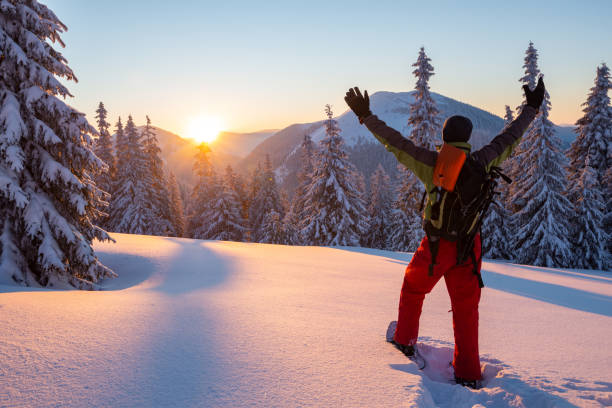 Adventurer stands with open arms in the winter mountains stock photo