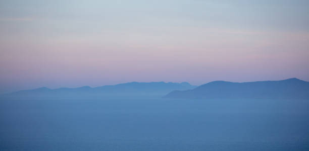 egeïsche zee en attica griekenland heuvels, pastel blauwe en roze tinten op zee en hemel achtergrond, - egeïsche zee stockfoto's en -beelden