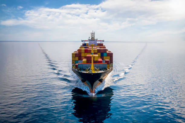 Aerial front view of a loaded container cargo vessel Aerial front view of a loaded container cargo vessel traveling over calm ocean freight transportation stock pictures, royalty-free photos & images
