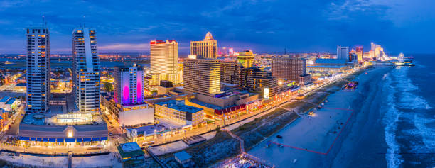 Aerial panorama of Atlantic City at dusk Aerial panorama of Atlantic City along the boardwalk at dusk. In the 1980s, Atlantic City achieved nationwide attention as a gambling resort and currently has nine large casinos. boardwalk stock pictures, royalty-free photos & images