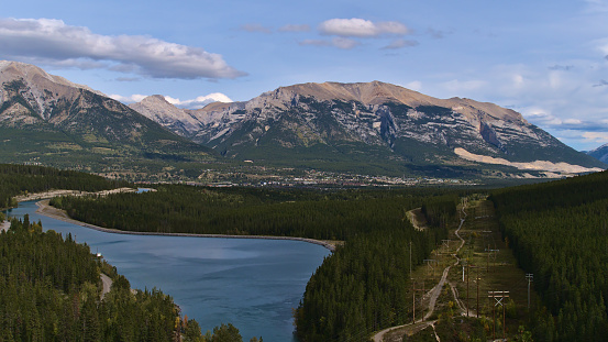 Beautiful aerial panoramic view over Bow Valley with city Canmore, Alberta, Canada in the Rocky Mountains with reservoir Rundle Forebay surrounded by forests viewed from Grassi Lakes Trail in fall.