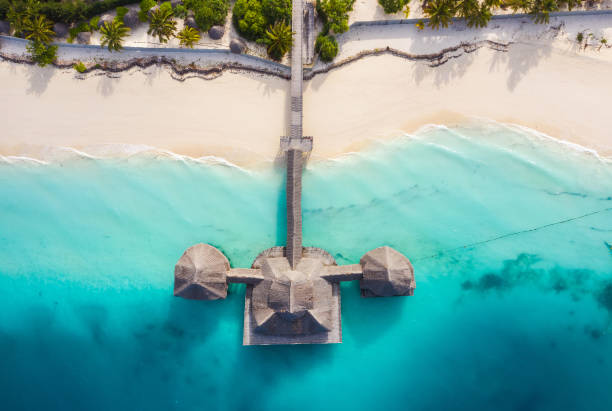 Aerial shot of the Stilt hut with palm thatch roof washed with turquoise Indian ocean waves on the white sand sandbank beach on Zanzibar island, Tanzania. stock photo