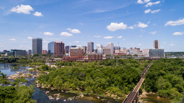 Aerial skyline of Downtown Richmond, Virginia. The distant view over the James River and surrounding parks and wooden natural areas. The railroad on the bridge. stock photo