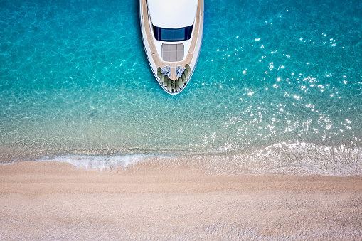 Aerial top down view of a luxury yacht moored at a paradise beach with turquoise sea and no people for summer time