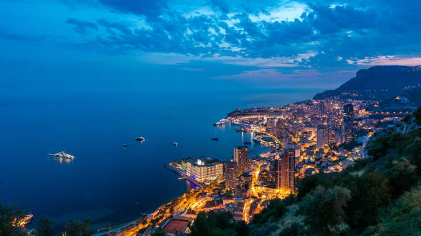 Aerial top view of Monaco from the grand corniche road day to night timelapse, Monaco France Aerial top view of Monaco from the grand corniche road day to night transition timelapse, Monaco France. Evening illumination. Reflections in water of harbor monaco as stock pictures, royalty-free photos & images