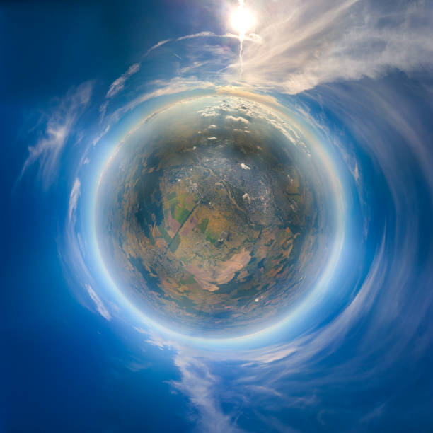 Aerial view from airplane window at high altitude of little planet earth covered with white thin layer of misty haze and distant clouds at sunset stock photo